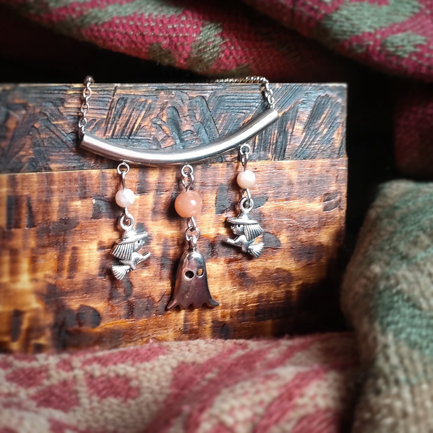 collier sur le theme d'halloween orné de perles de pierre de lune orangée et représentant deux petites sorcieres sur leur balais encadrant un fantome